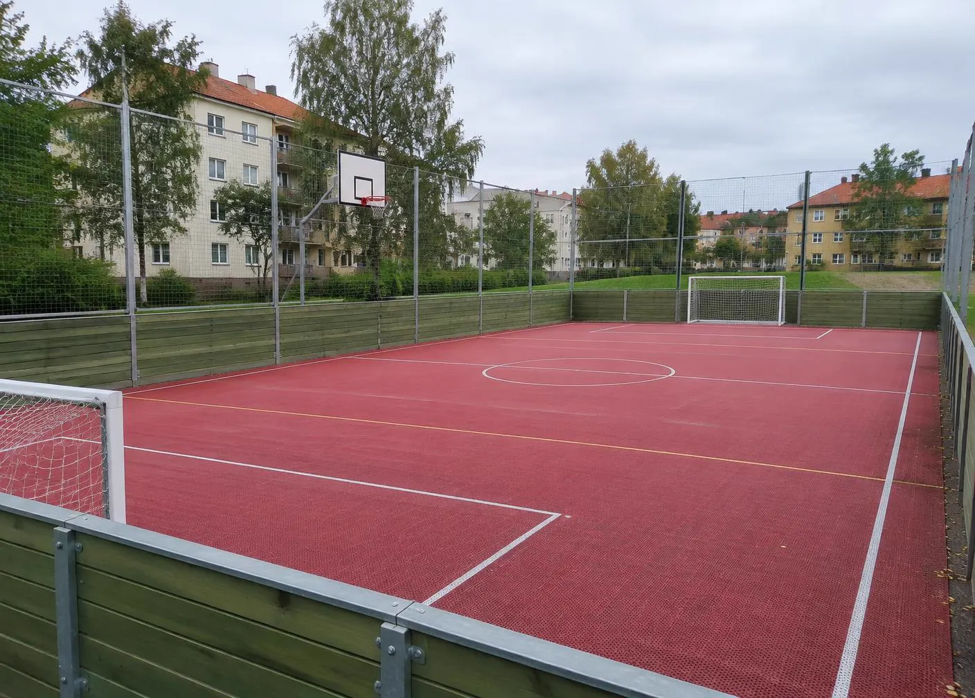 Inhägnad multisportyta med mål och basketkorg